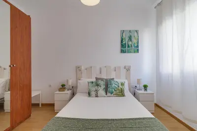 a white bedroom with a large bed with white sheets at Stylish Apartment In Gracia in Barcelona