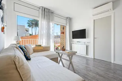 a white living room with a couch and a tv at Hauzify I Apartament Zulú Cubelles in Cubelles