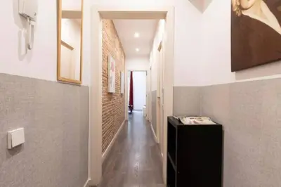 a hallway with a brick wall and a black cabinet at Canela Homes BARCELONA URQUINAONA in Barcelona