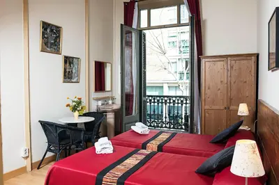 two beds in a room with a table and a window at Fashion House in Barcelona