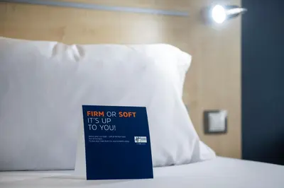 a sign sitting on top of a bed with a pillow at Holiday Inn Express Barcelona City 22@ by IHG in Barcelona