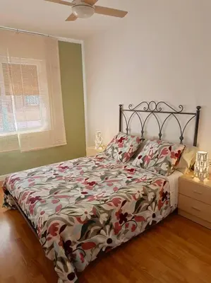 a bedroom with a bed with a floral comforter at Apartamento a 5' de la playa in Premiá de Mar