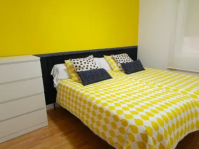 a yellow and white bed with black and white pillows at Apartamento a 5' de la playa in Premiá de Mar