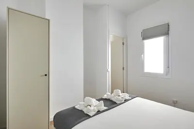 a white bedroom with mirrors and a bed with white towels at Ol Cute apartment in quiet Olivera st in Barcelona