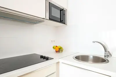 a white kitchen with a sink and a microwave at Centric apartment Gràcia in Barcelona