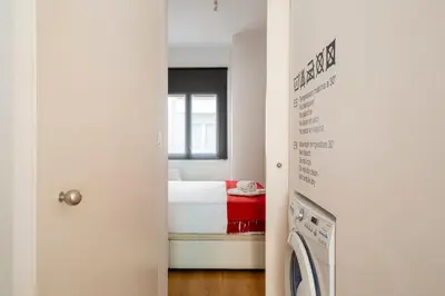 a small room with a bed and a washing machine at Centric apartment Gràcia in Barcelona