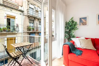 a red couch in a room with a balcony at Centric apartment Gràcia in Barcelona