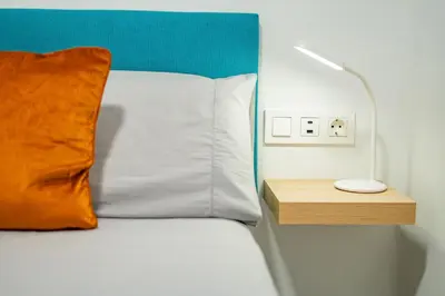 a bed with a orange pillow and a lamp on a night stand at Home365 · Barberá del Vallés · Barcelona in Barbera del Valles