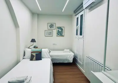 a small room with two beds and a window at Sweet BCN Laforja in Barcelona