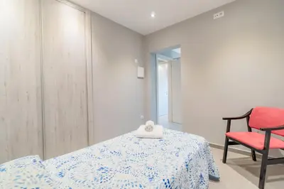 a bedroom with a bed and a red chair at Casa Majestic in Cunit