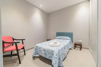 a small bedroom with a bed and a chair at Casa Majestic in Cunit