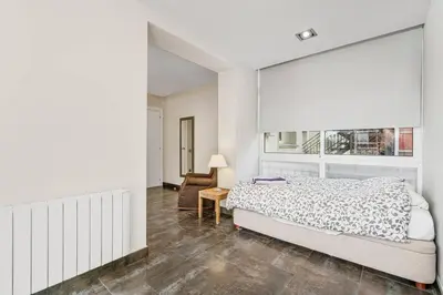 a white bedroom with a bed and a chair at Beachside Bliss in Castelldefels
