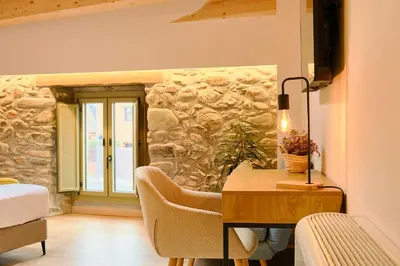 a bedroom with a desk and a stone wall at Hotel Molí Cardedeu in Cardedeu