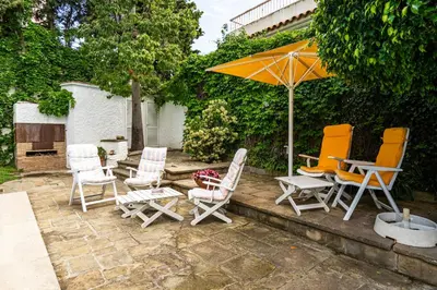 a group of chairs and an umbrella on a patio at Casa Mediterránea con jardín y piscina privada in Masnou