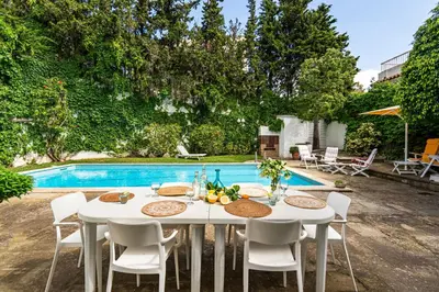 a white table and chairs next to a swimming pool at Casa Mediterránea con jardín y piscina privada in Masnou