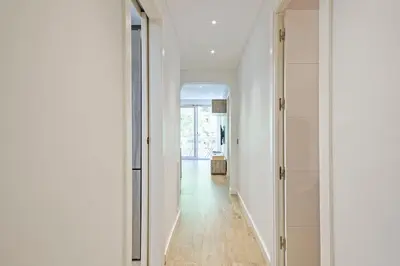 a hallway with white walls and wood floors and a white door at Habitat Apartments Pau in Barcelona