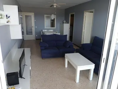 a living room with a blue couch and a table at Primera linea in Cunit