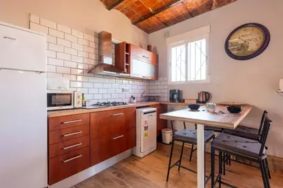 a kitchen with a table and a white refrigerator at Atico con Terraza en Fira Barcelona - Negocios y Turismo en Sants - Montjuic in Barcelona