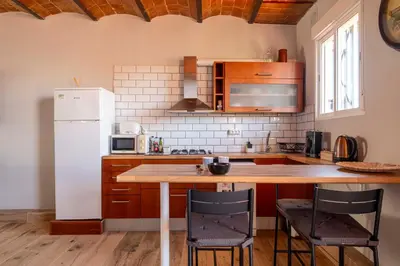 a kitchen with a wooden table and a white refrigerator at Atico con Terraza en Fira Barcelona - Negocios y Turismo en Sants - Montjuic in Barcelona