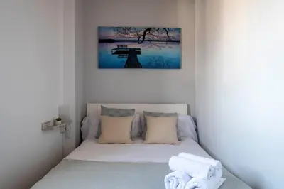 a bed in a white room with a picture on the wall at Atico con Terraza en Fira Barcelona - Negocios y Turismo en Sants - Montjuic in Barcelona