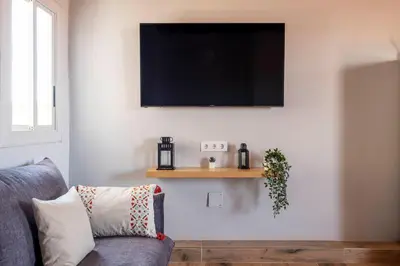 a living room with a couch and a tv on a wall at Atico con Terraza en Fira Barcelona - Negocios y Turismo en Sants - Montjuic in Barcelona
