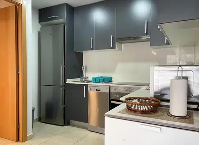 a kitchen with black cabinets and a basket on a counter at Apartment Marina in Vilanova i la Geltrú
