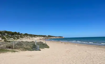 a beach with people walking on the sand and the ocean at Apartment Marina in Vilanova i la Geltrú