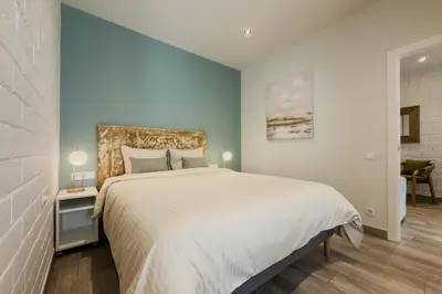 a bedroom with a large bed and a blue wall at Novus Homes Barcelona Santa Eulalia in Hospitalet de Llobregat