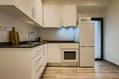 a kitchen with white cabinets and a refrigerator at Novus Homes Barcelona Santa Eulalia in Hospitalet de Llobregat