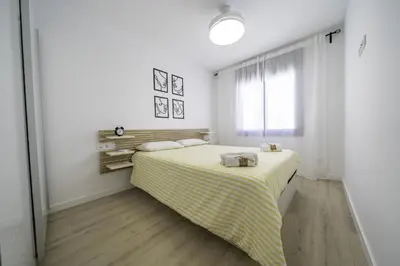 a bedroom with a bed with a yellow and white blanket at HomeHolidaysRentals Kala - Costa Barcelona in Pineda de Mar