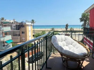 a white chair sitting on a balcony overlooking the beach at Golden hours by the sea in Castelldefels