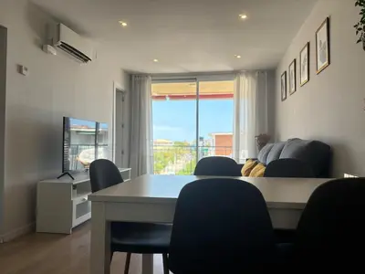 a dining room with a table and chairs and a window at Golden hours by the sea in Castelldefels