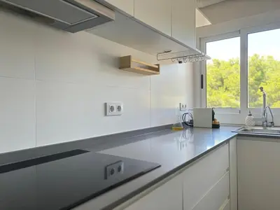 a white kitchen with a sink and a window at Golden hours by the sea in Castelldefels