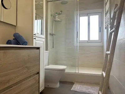 a bathroom with a shower and a toilet and a window at Golden hours by the sea in Castelldefels