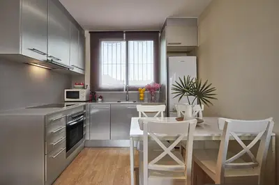 a kitchen with a table and some white chairs at BBarcelona Urban Apartments in Barcelona