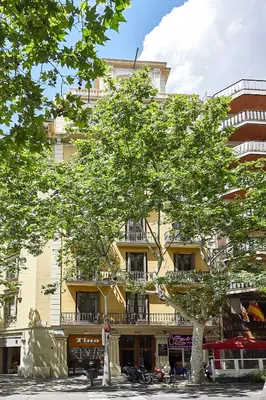 a tall yellow building with a tree in front of it at BBarcelona Urban Apartments in Barcelona
