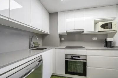 a white kitchen with white cabinets and a sink at HomeholidayRentals Singular - Costa Barcelona in Pineda de Mar