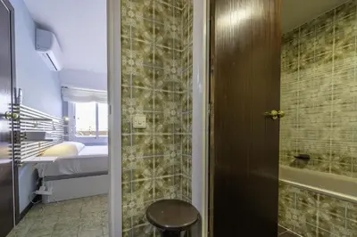 a bathroom with a walk in shower next to a bed at HomeholidayRentals Singular - Costa Barcelona in Pineda de Mar