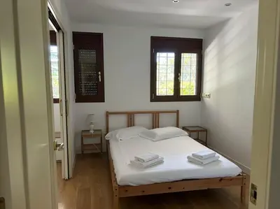 a bedroom with a bed with white sheets and two windows at Vivenda de luxe a Barcelona in Sant Cugat del Vallès