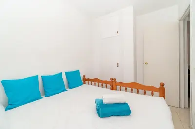 a bedroom with a white bed with blue pillows at Apartamento Acqua Fresca in Cunit