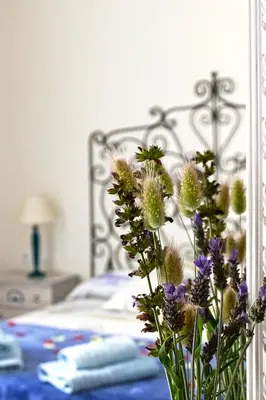 a vase filled with purple flowers next to a bed at La Llar de la Kim, ideal familias in Arenys de Mar
