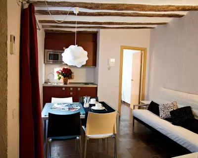 a kitchen and a living room with a table and a couch at Apartaments Ciutat Vella in Barcelona