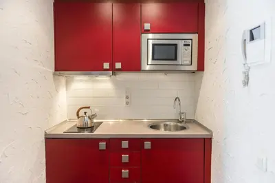 a kitchen with red cabinets and a sink and a microwave at Apartaments Ciutat Vella in Barcelona