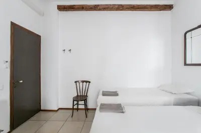 a bedroom with two beds and a chair at Canela Homes BARCELONA GÒTIC in Barcelona