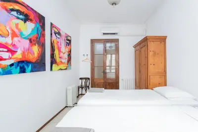 a bedroom with a white bed and a painting on the wall at Canela Homes BARCELONA GÒTIC in Barcelona