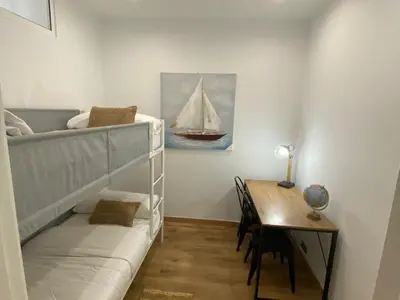 a bedroom with a bunk bed with a desk and a sailboat painting at Matarolux26 in Mataró