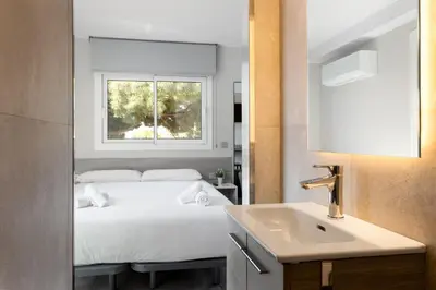 a bedroom with a bed with a sink and a window at Aparthotel Vilassar in Vilassar de Mar