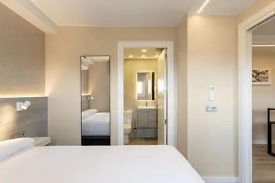 a bedroom with a white bed and a bathroom at Aparthotel Vilassar in Vilassar de Mar
