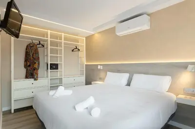 a bedroom with a large white bed and a tv at Aparthotel Vilassar in Vilassar de Mar