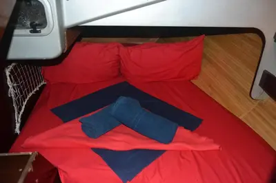 a red bed with two red pillows at COSY BOAT FLAT at BARCELONA BEACH in Barcelona